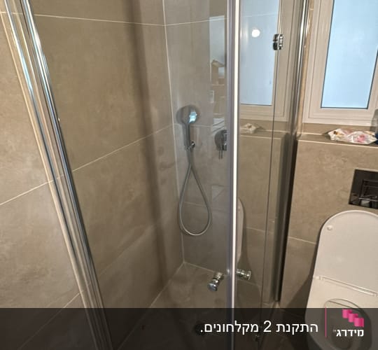 מקלחון זכוכית בחדר אמבטיה עם ראש מקלחת עגול